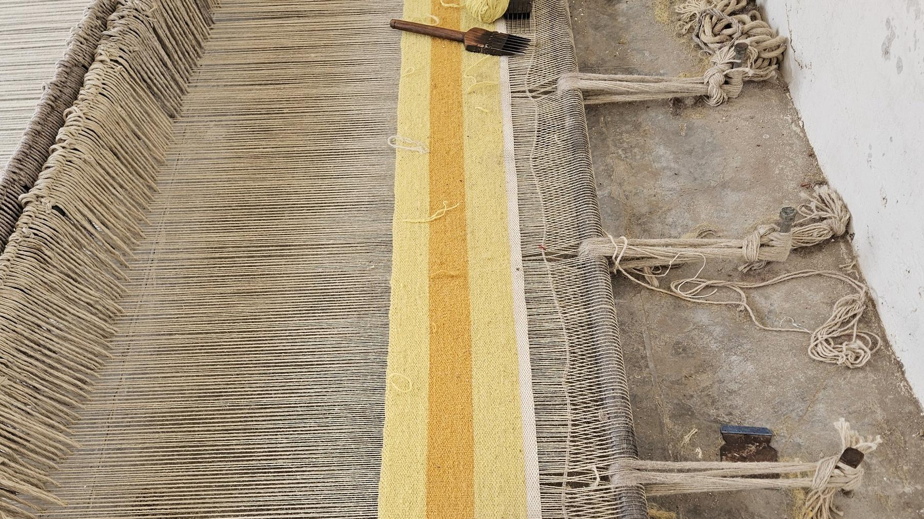 A yellow-striped runner half-woven on the loom